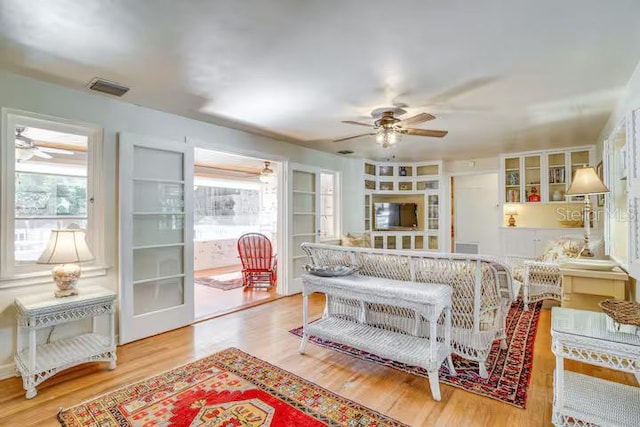 living room with visible vents, a ceiling fan, and wood finished floors