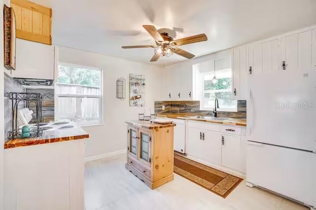 kitchen featuring ceiling fan, white refrigerator, white cabinetry, and sink