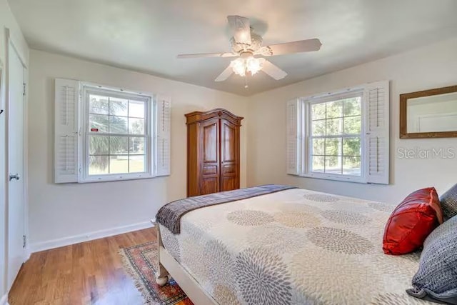 bedroom featuring ceiling fan, wood-type flooring, and multiple windows