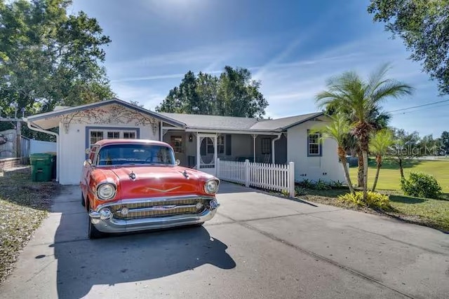 ranch-style house featuring concrete driveway and fence