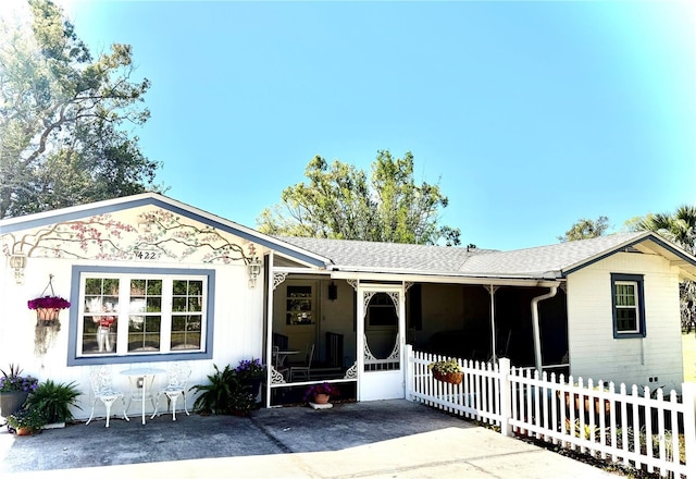 ranch-style home with a sunroom, fence, and roof with shingles