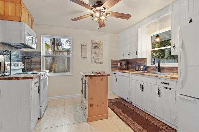 kitchen featuring a ceiling fan, white appliances, baseboards, a sink, and wood counters