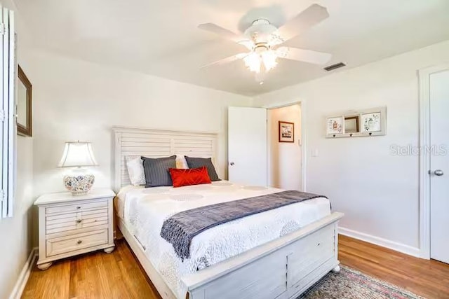 bedroom with baseboards, visible vents, and wood finished floors
