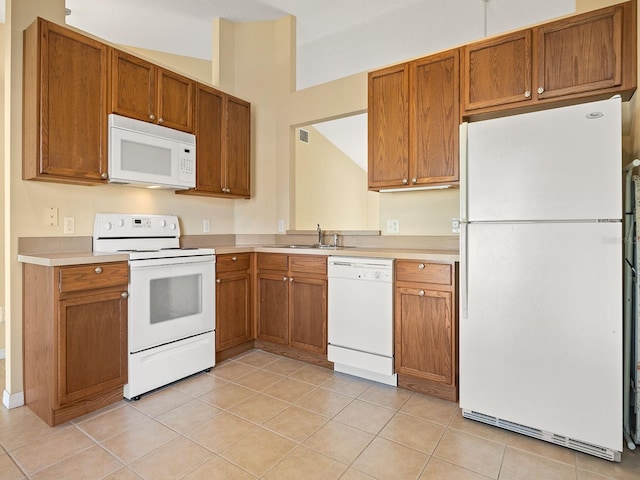 kitchen with vaulted ceiling, sink, light tile patterned floors, and white appliances