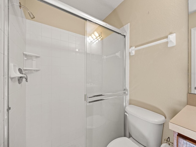 bathroom with a shower with door, vanity, and toilet