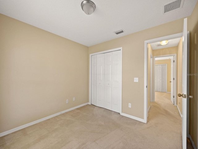 unfurnished bedroom with light carpet and a closet