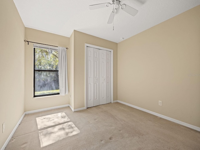 unfurnished bedroom with ceiling fan, a closet, and light colored carpet