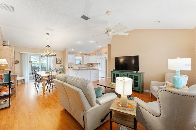 living room featuring ceiling fan with notable chandelier, light hardwood / wood-style floors, and lofted ceiling