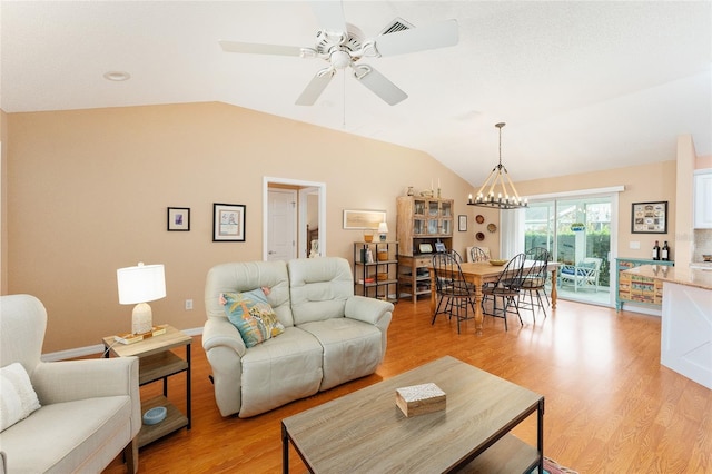 living room with ceiling fan with notable chandelier, light hardwood / wood-style flooring, and vaulted ceiling