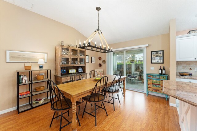 dining room with an inviting chandelier, light wood-type flooring, and vaulted ceiling