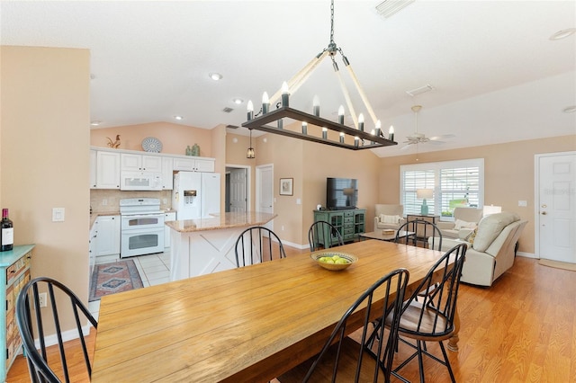 dining room featuring vaulted ceiling, light hardwood / wood-style floors, and ceiling fan with notable chandelier