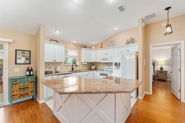 kitchen with a center island, sink, hanging light fixtures, white appliances, and white cabinets