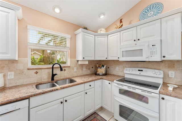 kitchen featuring vaulted ceiling, sink, white cabinets, and white appliances