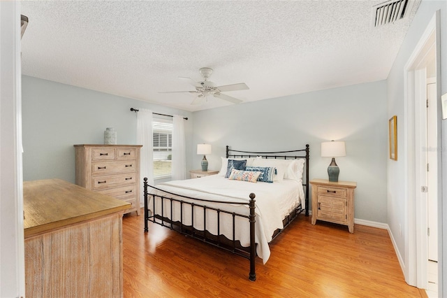 bedroom featuring ceiling fan, light wood-type flooring, and a textured ceiling