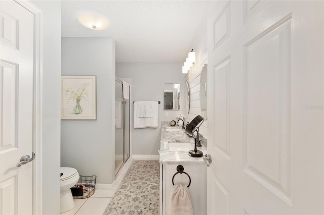 bathroom with vanity, a textured ceiling, toilet, and a shower with door