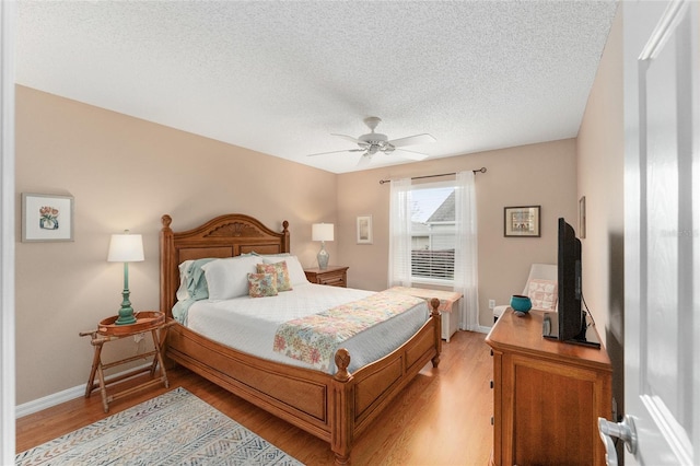 bedroom with ceiling fan, light hardwood / wood-style flooring, and a textured ceiling