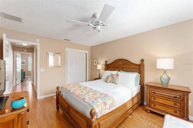 bedroom with a textured ceiling, light wood-type flooring, a closet, and ceiling fan