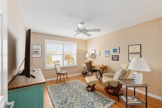 living area featuring ceiling fan, a textured ceiling, and hardwood / wood-style flooring