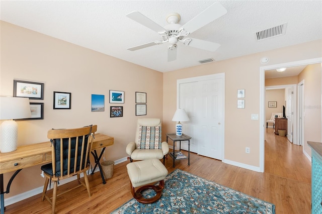 home office featuring ceiling fan, a textured ceiling, and light wood-type flooring