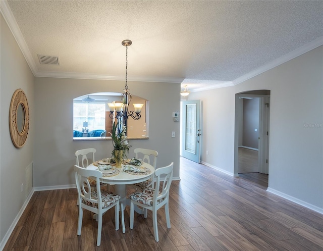 dining space with a textured ceiling, crown molding, and dark hardwood / wood-style flooring