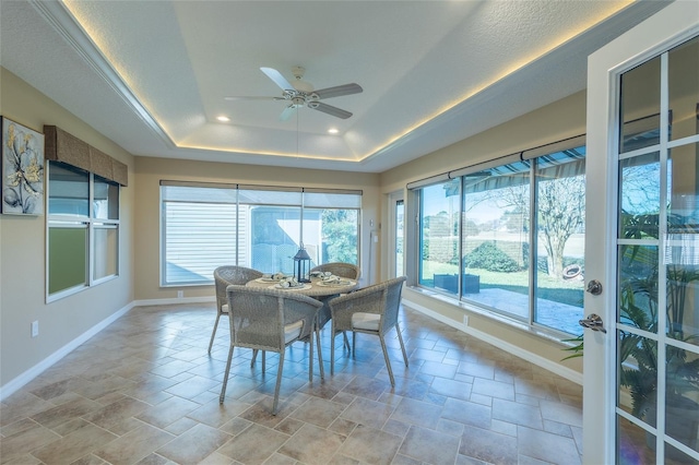 sunroom / solarium with ceiling fan and a tray ceiling