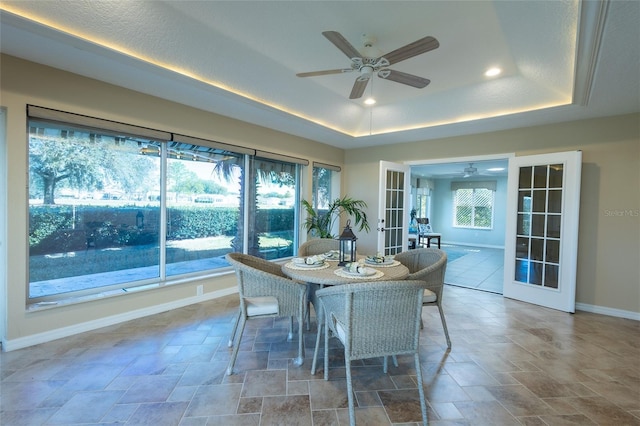 dining space with a raised ceiling, ceiling fan, and french doors