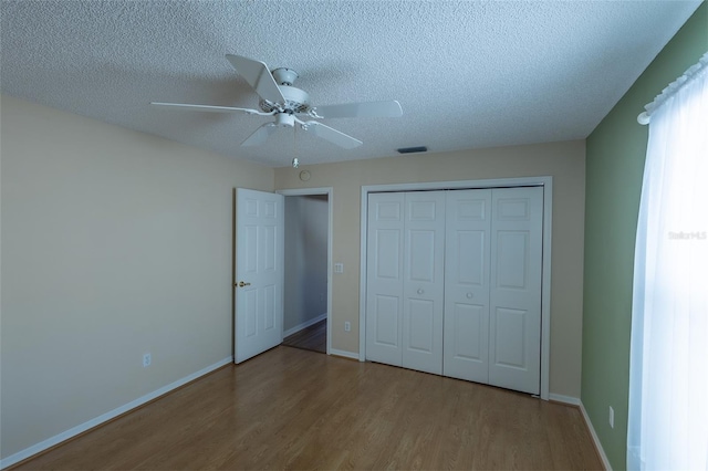 unfurnished bedroom with ceiling fan, light hardwood / wood-style floors, a closet, and a textured ceiling