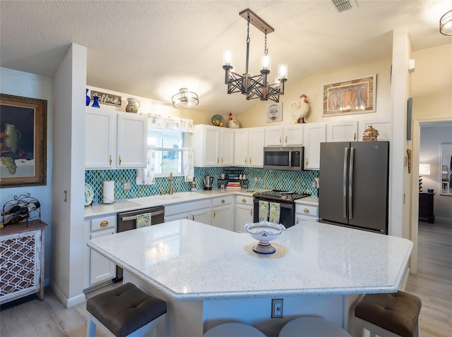 kitchen with a breakfast bar area, decorative light fixtures, tasteful backsplash, and appliances with stainless steel finishes