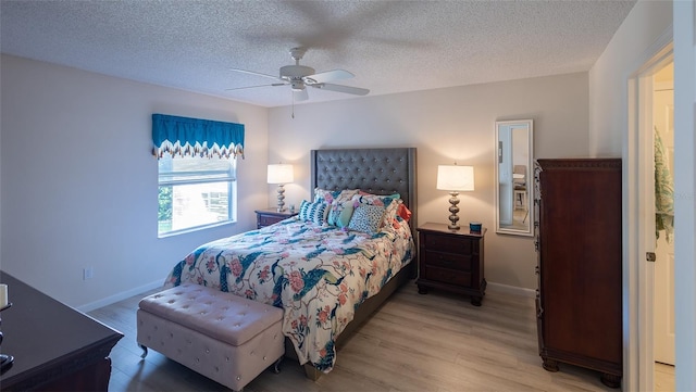 bedroom with a textured ceiling, ceiling fan, and light wood-type flooring