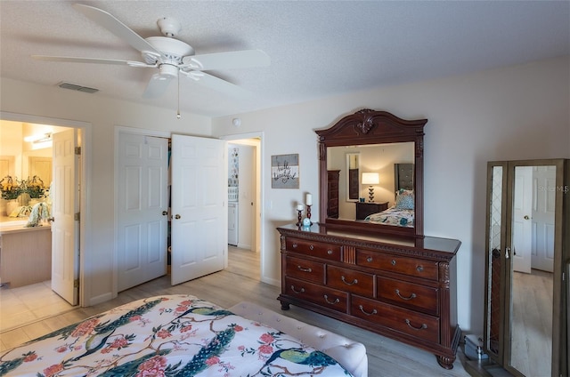 bedroom with ceiling fan, ensuite bathroom, a closet, and a textured ceiling