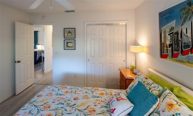 bedroom with ceiling fan, light hardwood / wood-style floors, and a closet