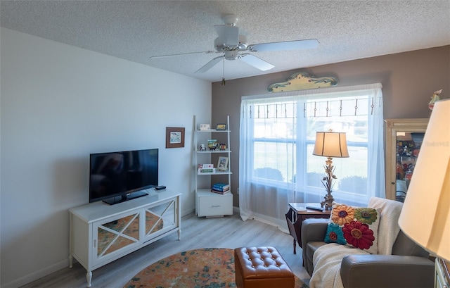 living room featuring a textured ceiling, light wood-type flooring, and ceiling fan