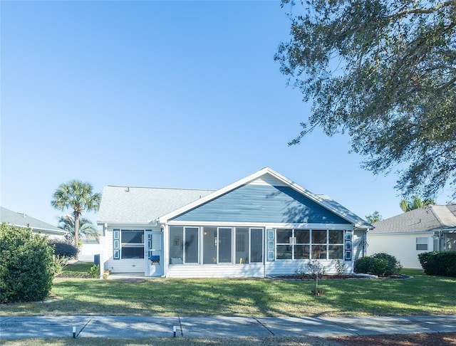 rear view of house featuring a lawn and a sunroom