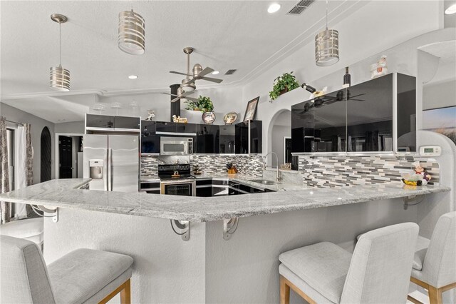 kitchen with pendant lighting, sink, stainless steel appliances, decorative backsplash, and kitchen peninsula