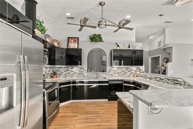 kitchen featuring sink, appliances with stainless steel finishes, backsplash, vaulted ceiling, and kitchen peninsula