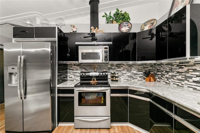 kitchen with stainless steel appliances, backsplash, light stone counters, and light hardwood / wood-style floors