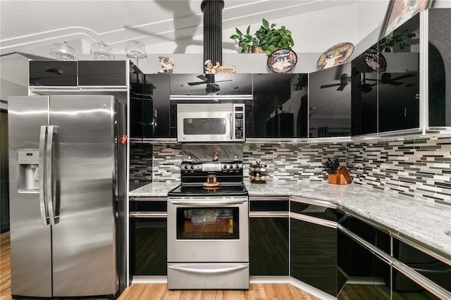 kitchen featuring tasteful backsplash, light stone countertops, light hardwood / wood-style flooring, and stainless steel appliances