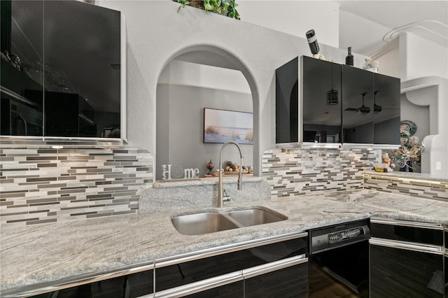 kitchen featuring light stone counters, sink, backsplash, and black dishwasher