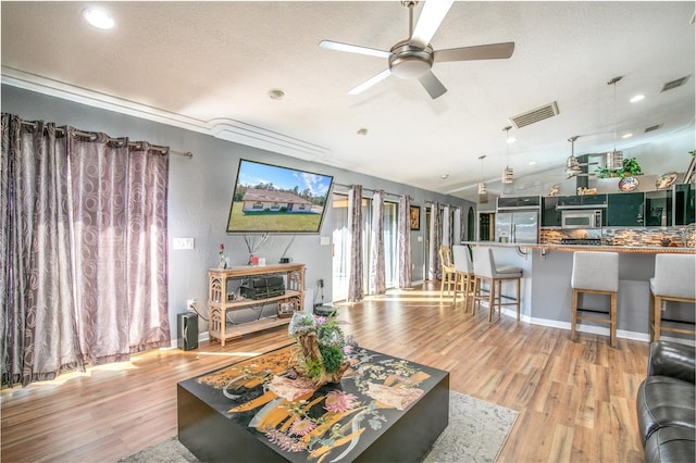 living room with ceiling fan, vaulted ceiling, light hardwood / wood-style flooring, and a textured ceiling