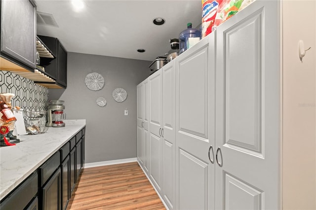 kitchen with light stone countertops, light hardwood / wood-style floors, and decorative backsplash