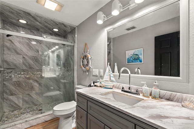 bathroom with hardwood / wood-style flooring, toilet, vanity, and walk in shower