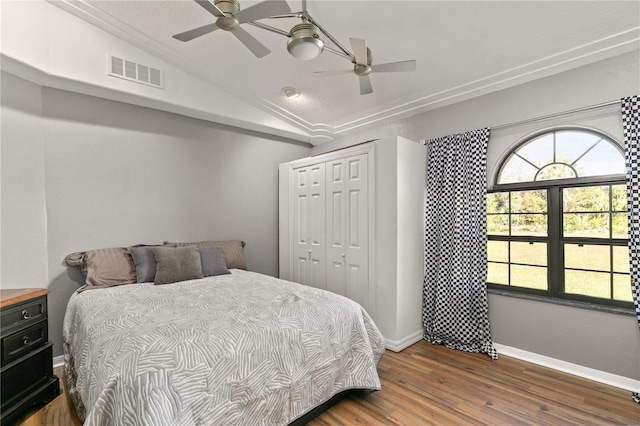 bedroom with vaulted ceiling, dark hardwood / wood-style flooring, ceiling fan, and a closet