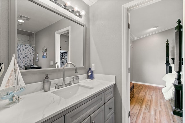 bathroom with hardwood / wood-style flooring, vanity, and ornamental molding