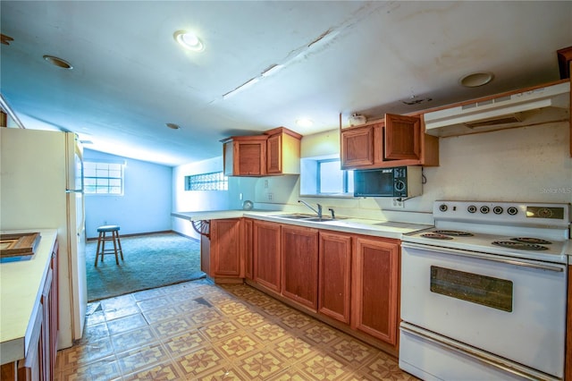 kitchen with sink, white appliances, vaulted ceiling, and kitchen peninsula