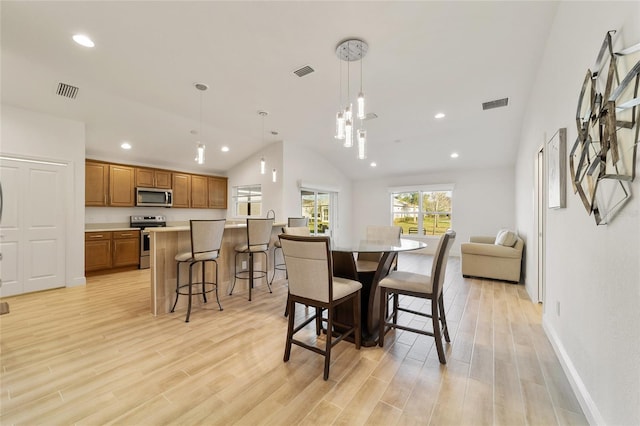 dining space with light wood-type flooring and vaulted ceiling