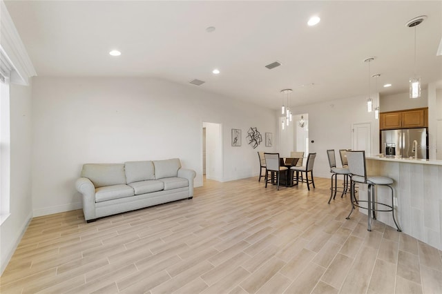 living room with light hardwood / wood-style floors and vaulted ceiling