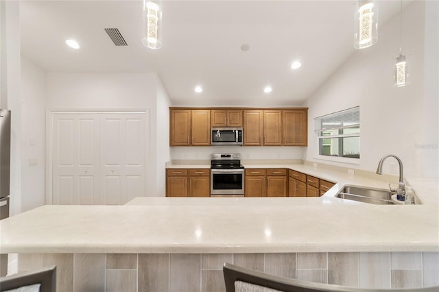 kitchen with sink, hanging light fixtures, kitchen peninsula, a breakfast bar area, and appliances with stainless steel finishes