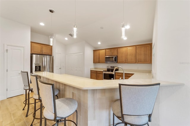 kitchen with a kitchen bar, kitchen peninsula, pendant lighting, and appliances with stainless steel finishes