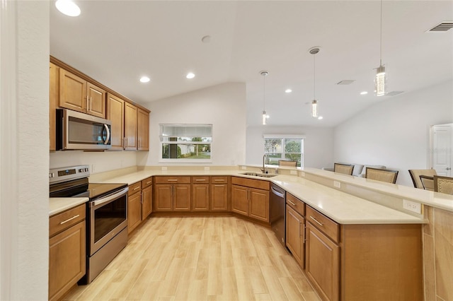 kitchen with hanging light fixtures, sink, vaulted ceiling, appliances with stainless steel finishes, and a kitchen bar