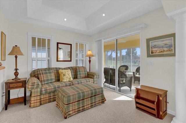 carpeted living room featuring plenty of natural light, a raised ceiling, and decorative columns